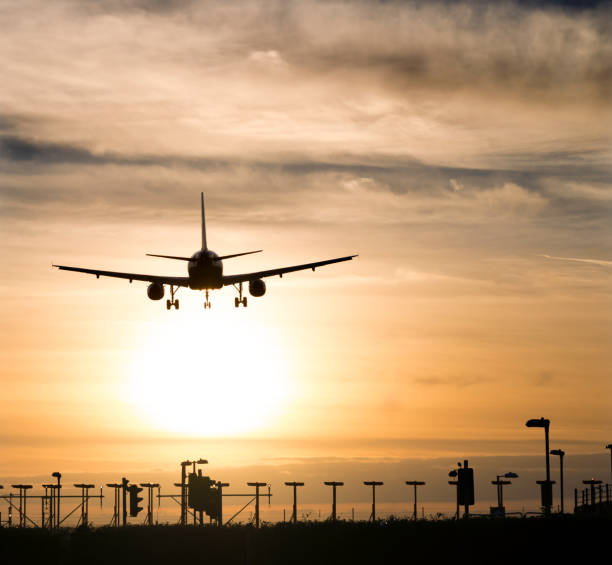 Airplane landing in sunset Airplane approaching the landing strip at sunset. Heathrow, London, UK. heathrow airport stock pictures, royalty-free photos & images