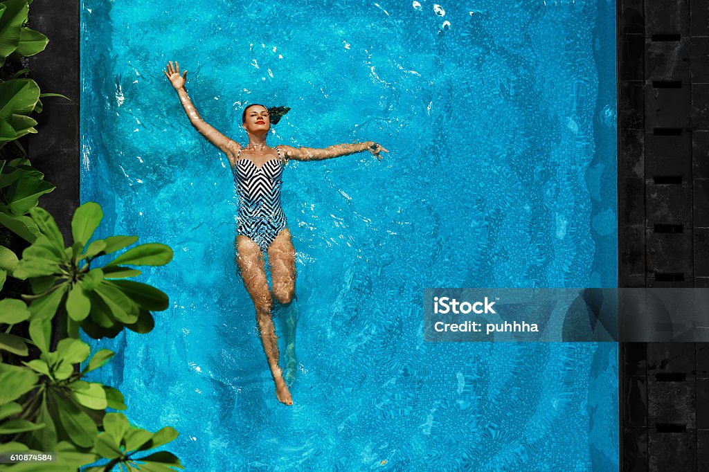 Woman Relaxing In Swimming Pool Water. Summer Holidays Vacation. Woman In Pool Water. Beautiful Happy Girl With Sexy Fit Body Relaxing, Floating In Swimming Pool At Spa Hotel. Summer Holidays Vacation. Healthy Lifestyle. Wellness, Beauty, Health Concept. Recreation Swimming Pool Stock Photo