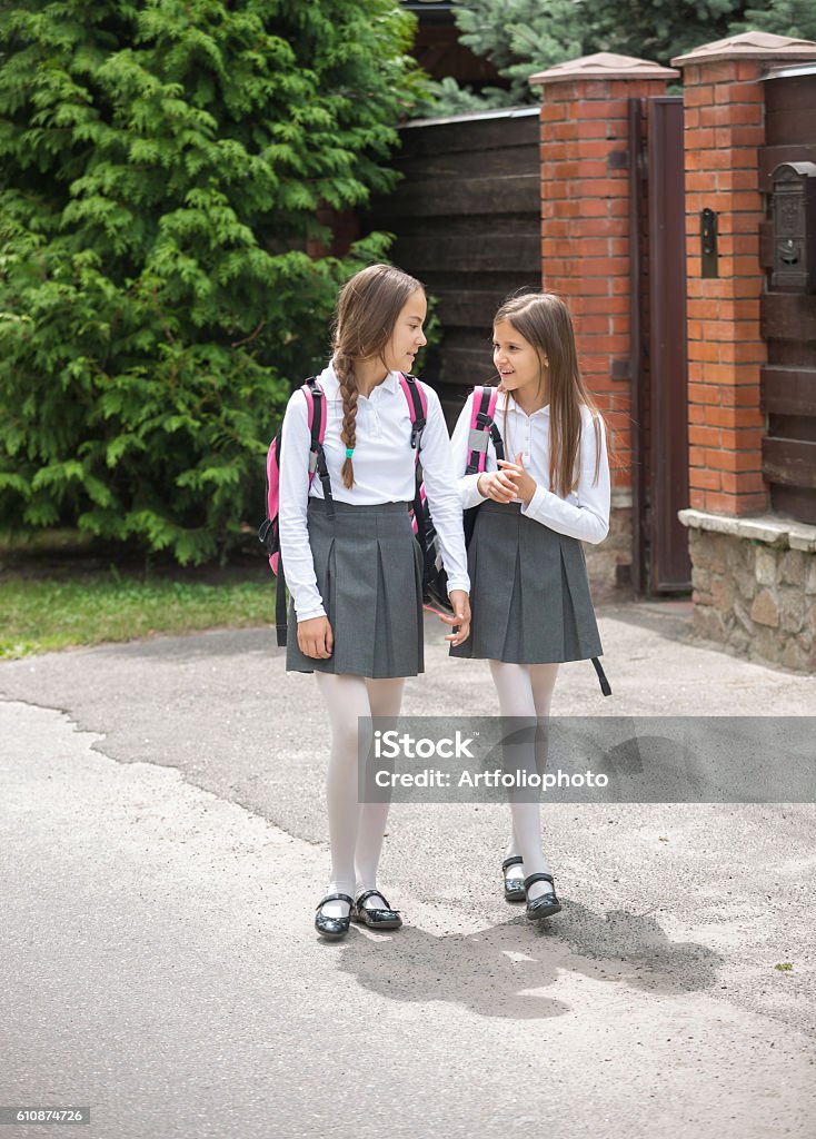 Cute girls in uniform walking to school and chatting Two cute girls in uniform walking to school and chatting School Uniform Stock Photo