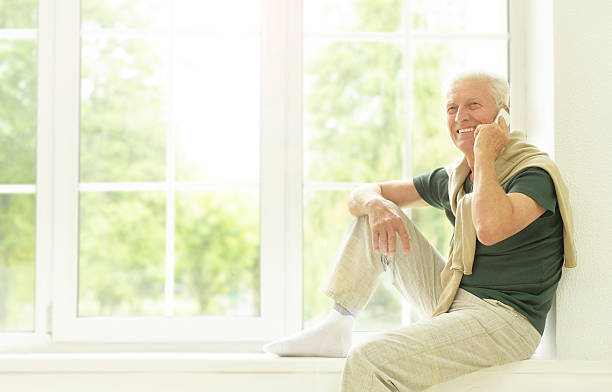istock senior man with phone at home 610875264