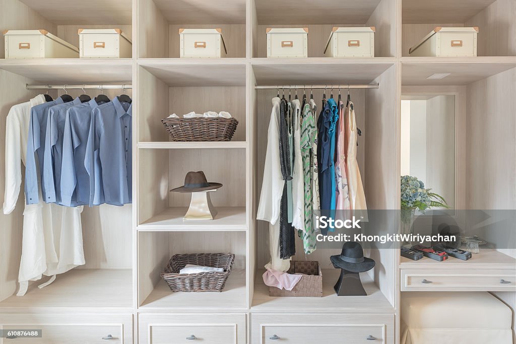 modern wooden wardrobe with clothes hanging on rail modern wooden wardrobe with clothes hanging on rail in walk in closet design interior Closet Stock Photo