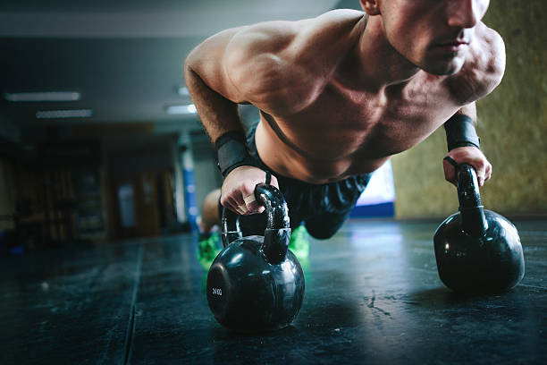 istock Young man doing pushups with kettle bells at the gym 610877428
