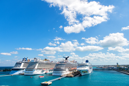 Nassau, Bahamas - February 18, 2016: Large luxury cruise ships of Carnival, Norwegian and Royal Caribbean cruise lines docked in port of Nassau, Bahamas on sea water and cloudy sky background