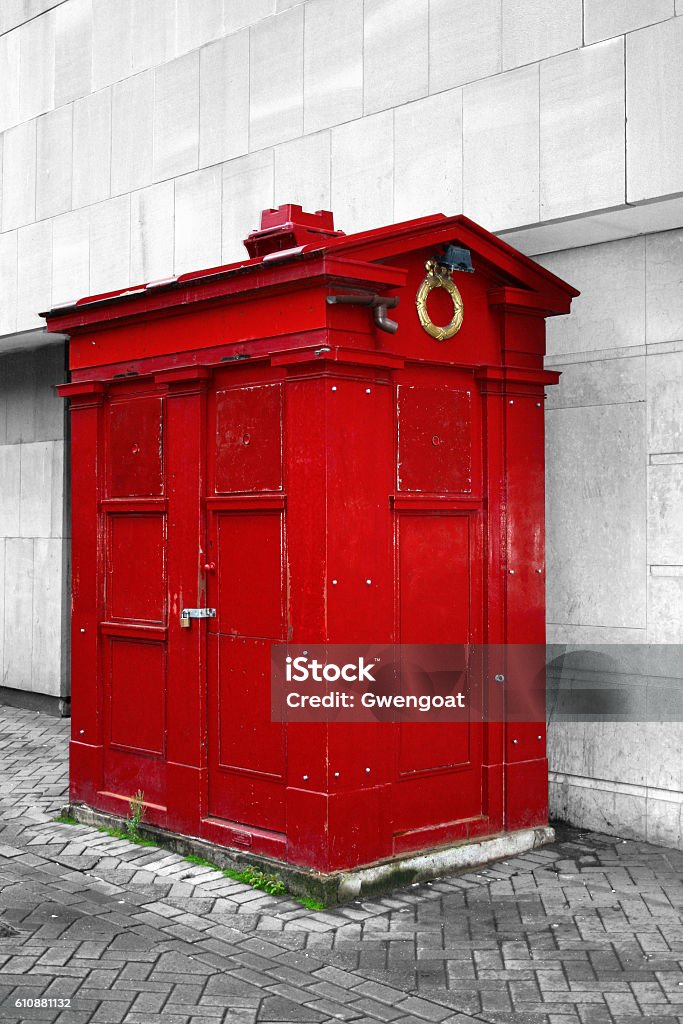 Red Police Information Box in Edinburgh Normally blue, the Police Information Box in Edinburgh can be found painted in other colors since, generally, they are used for another purpose. This one is painted in red and to emphasis the picture, the rest is in black and white. Black And White Stock Photo