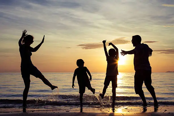 Photo of Silhouette of happy family who playing on the beach.