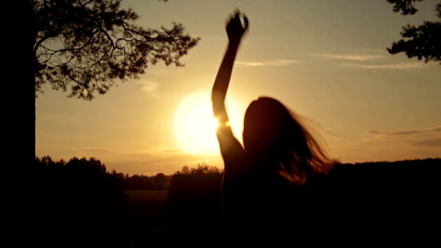 Young happy woman jumping, dancing and having fun in the forest at sunset
