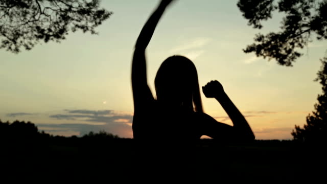 Young woman jumping and dancing in the forest after sunset