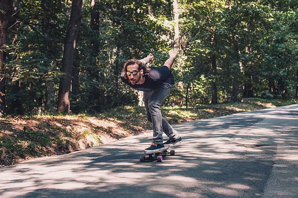 Photo of Skateboarder ride a longboard through the forest