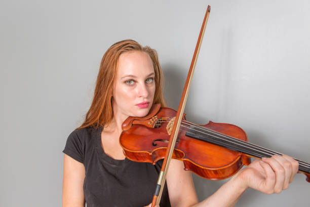 istock Young red haired female playing violin in istanbul turkey 610945806