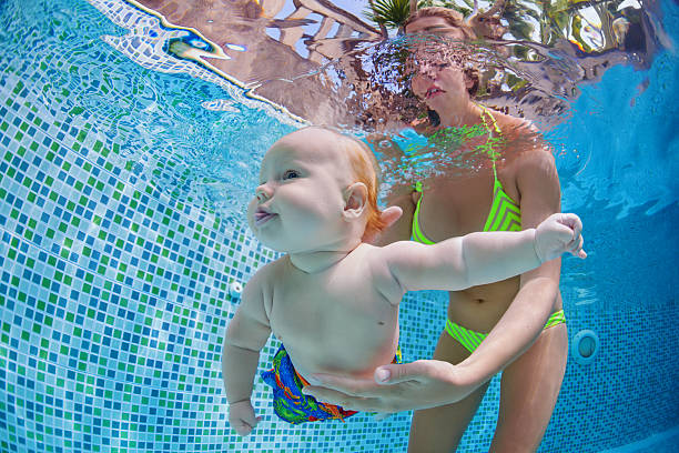 istock Little baby dive underwater with fun in swimming pool 610946474
