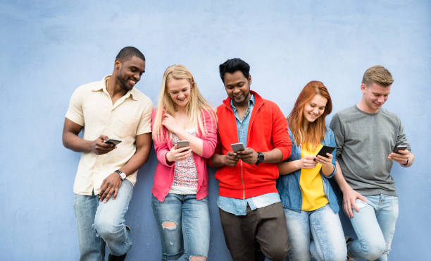 adicción a las redes sociales personas que usan el teléfono inteligente - adicto grupo de jóvenes amigos usando teléfonos móviles fotografías e imágenes de stock