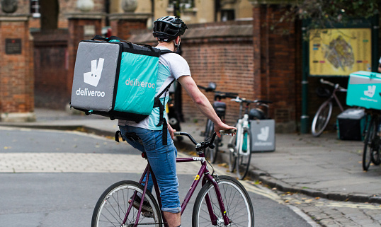 York, UK - September 28, 2016.A cyclist from the increasingly popular take away delivery company Deliveroo speeding through city streets with a hot food delivery from take aways and restaurants to homes.
