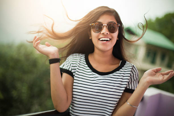 piękna dziewczyna w okularach przeciwsłonecznych ciesząc się świeżym powietrzem na balkonie. - teenage girls pretty smile looking at camera waist up zdjęcia i obrazy z banku zdjęć