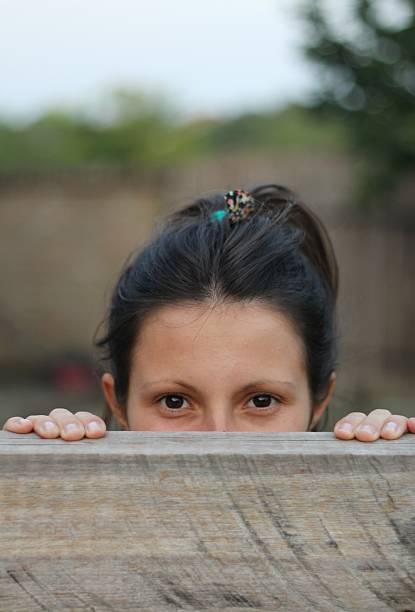 mädchen schaut über zaun - stockbild - fence child neighbor peeking stock-fotos und bilder