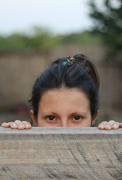 dziewczyna patrzy przez płot - zdjęcie stockowe - fence child neighbor peeking zdjęcia i obrazy z banku zdjęć