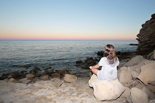 istock Girl meditating on a beach 610951498