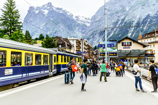 Grindelwald, Switzerland - July 08, 2016: Multiethnic group of tourists on the platform of the railway station at the alpine resort of Grindelwald in the Bernese Oberland, Switzerland. Famous for its views of the north face of the Eiger and as the bottom station for the trip to the Jungfrau, the village is always packed with tourists during the summer months.