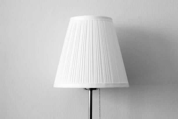 istock Small table lamp with white lampshade with wall background 610953500
