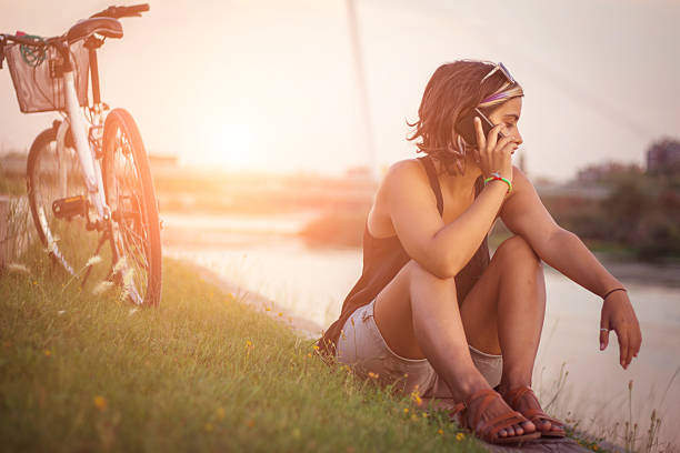 istock Happy girl talking on smart phone sitting on river side 610953678