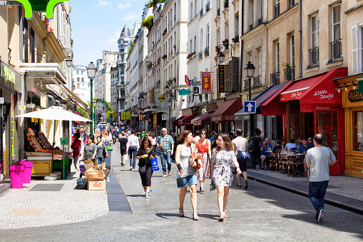 Paris, France - July 8, 2016: People walk on Rue Montorgueil street on sunny day in Paris. Cafes, little shops and French architecture style buildings are in the view.