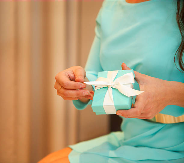 istock Woman holding a small gift box with white ribbon 610956092