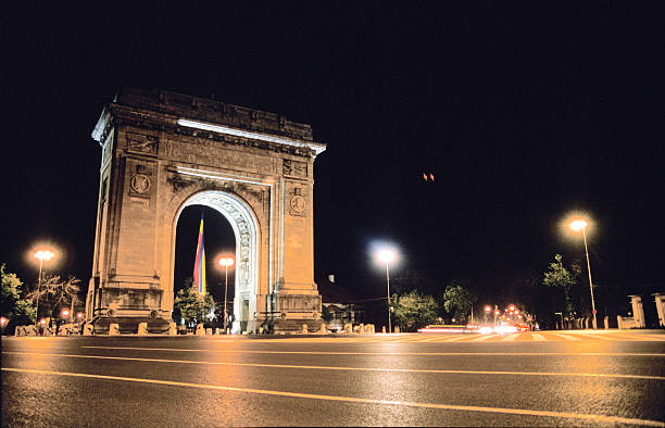 Triumphal Arch in Bucharest, Romania at night. Roads in the foreground.