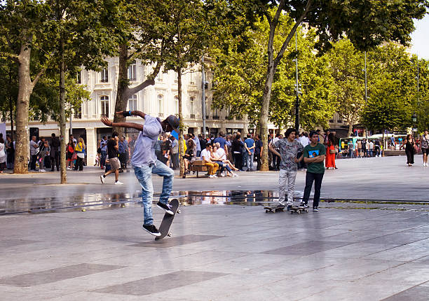 A young Caucasian couple engages in a skateboarding activity. The man, in plaid attire holding a skateboard, walks alongside a woman in white, highlighting an active urban lifestyle.