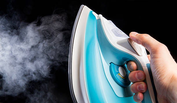 istock Modern iron in hand blowing off steam 610957048