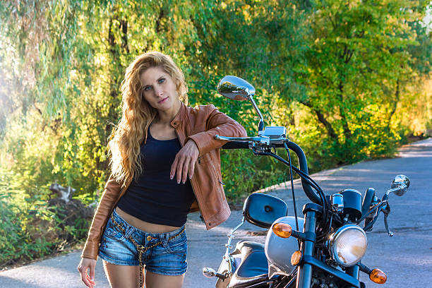 Woman from behind. A young blond woman goes through the asphalt road.