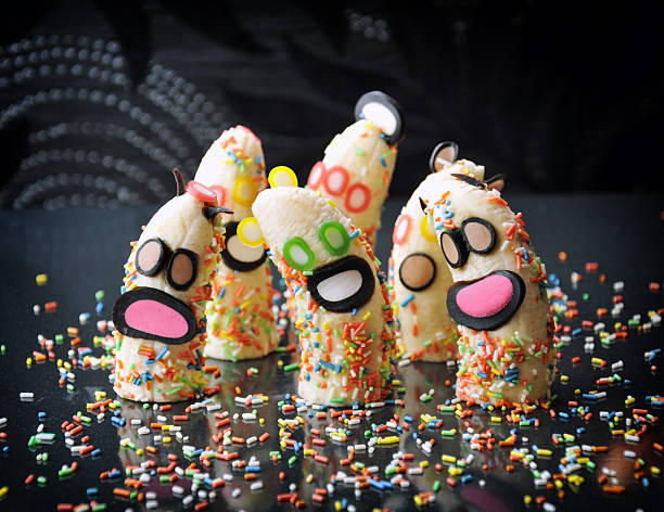 Halloween banana monsters with candy faces on dark background