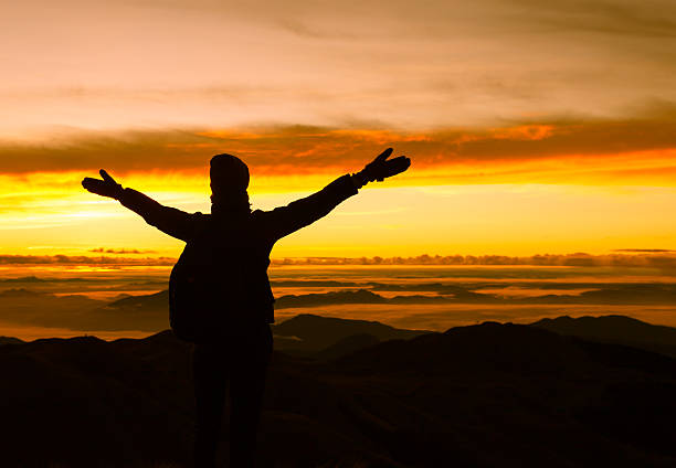 istock Cheering woman hiker open arms at mountain peak 610962490