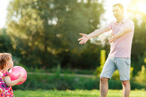 istock Dad with little daughter playing ball on lawn 610964282