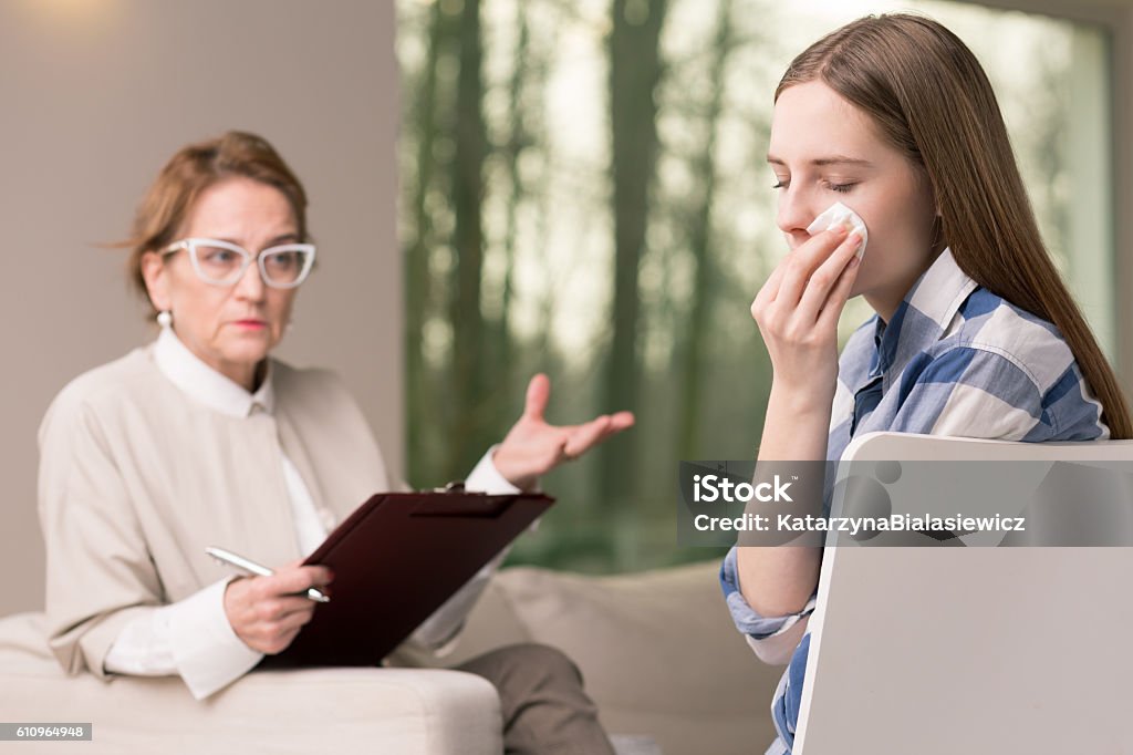 Crying is not a weakness manifestation Teenage girl sitting in the therapy room with her therapist and crying Adolescence Stock Photo