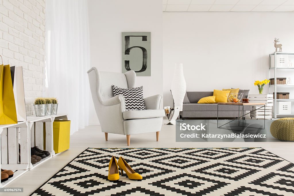 Agreeable place to rest a bit after an office day Very spacious living room in white, with yellow decorations and high-heeled shoes in the middle of a modern carpet Home Decor Stock Photo