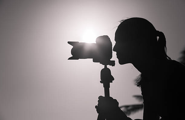 Female photographer taking pictures outdoor Silhouette of female photographer taking pictures outdoors. black and white portrait photographers stock pictures, royalty-free photos & images