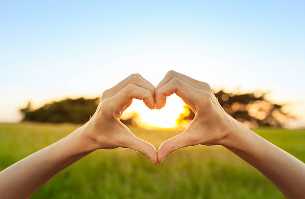 cuore a forma di mano contro il tramonto - heart shape healthy lifestyle valentines day romance foto e immagini stock
