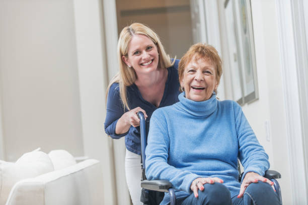senior femme en fauteuil roulant avec le nourricier à la maison - community outreach home caregiver care cheerful photos et images de collection