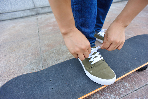 skateboarder tying shoelace at city