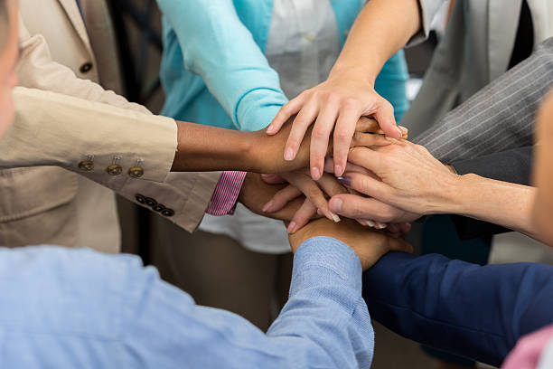 istock Diverse team of professionals with hands in huddle 610976242