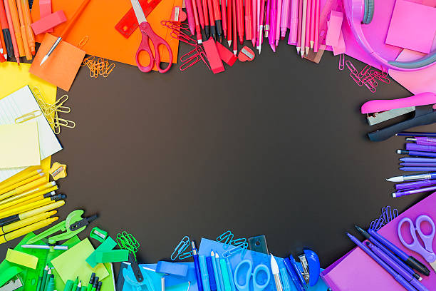 Full border of multi colored school supplies Full border of vibrant multi colored office supplies on chalkboard background. Border of colorful pens, pencils, markers, notebooks, paperclips, and other school supplies. Back to school theme. stapled paper stock pictures, royalty-free photos & images