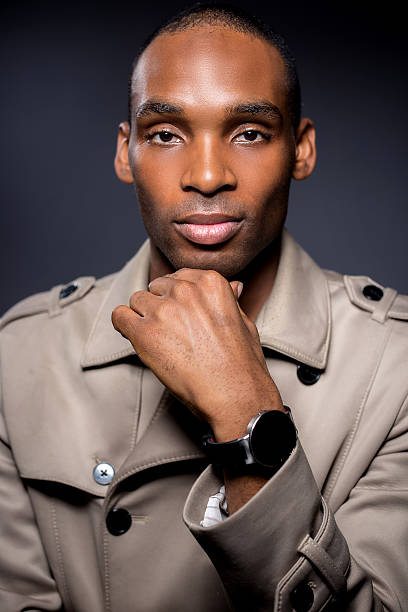 Fashionable male model wearing fall fashion style beige coat with smartwatch.  The man is wearing a stylish jacket and modern wearable tech.  The image depicts technology with chic fashion.