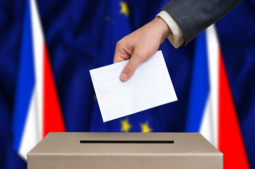 Referendum in France. The hand of man putting his vote in the ballot box. France and European Union flags on background. Frexit.