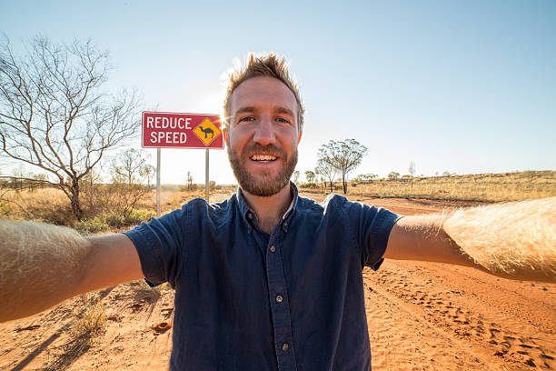 istock Selfie of young man standing by Camel warning sign 610981288