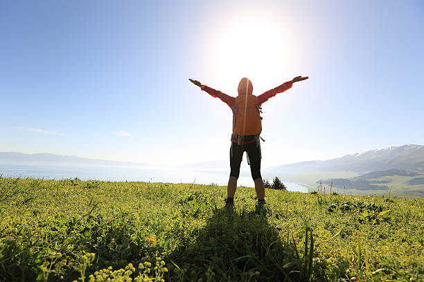 istock cheering young woman backpacker open arms at mountain peak 610983080
