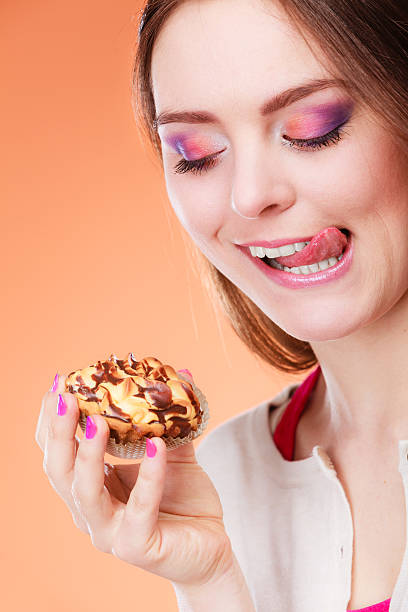 istock woman holds cake in hand licking lips 610983830