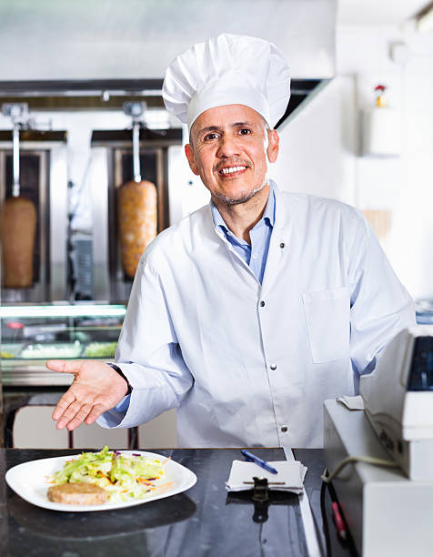 istock Cheerful mature man cook serving fresh kebab dish on plate 610984518