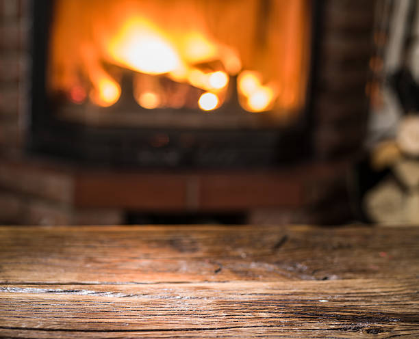 istock Old wooden table and fireplace with warm fire. 610985240