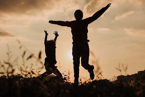 istock father and son jumping at sunset sky 610986486