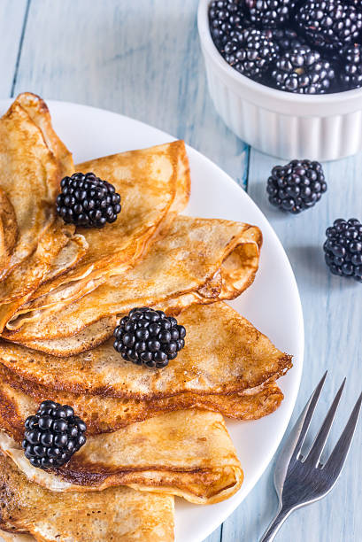 Crepes with blackberries on the wooden table