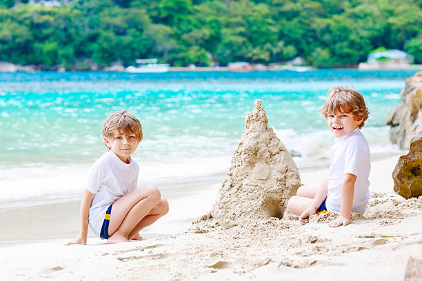 istock Two kid boys building sand castle on tropical beach 610987310